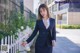 A woman in a business suit standing next to a fence.