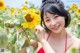 A woman in a red dress standing in a field of sunflowers.