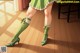 A woman in a green dress and green shoes standing on a wooden floor.