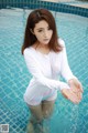 A woman in a white shirt is standing in a pool.