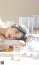 A woman laying on a wooden table next to glasses of water.