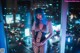 A woman in a fishnet bodysuit standing in front of a window.