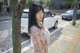 A woman standing next to a tree on a city street.