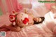 A woman laying on a bed holding a stuffed strawberry.