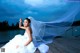 A woman in a wedding dress sitting on a dock.